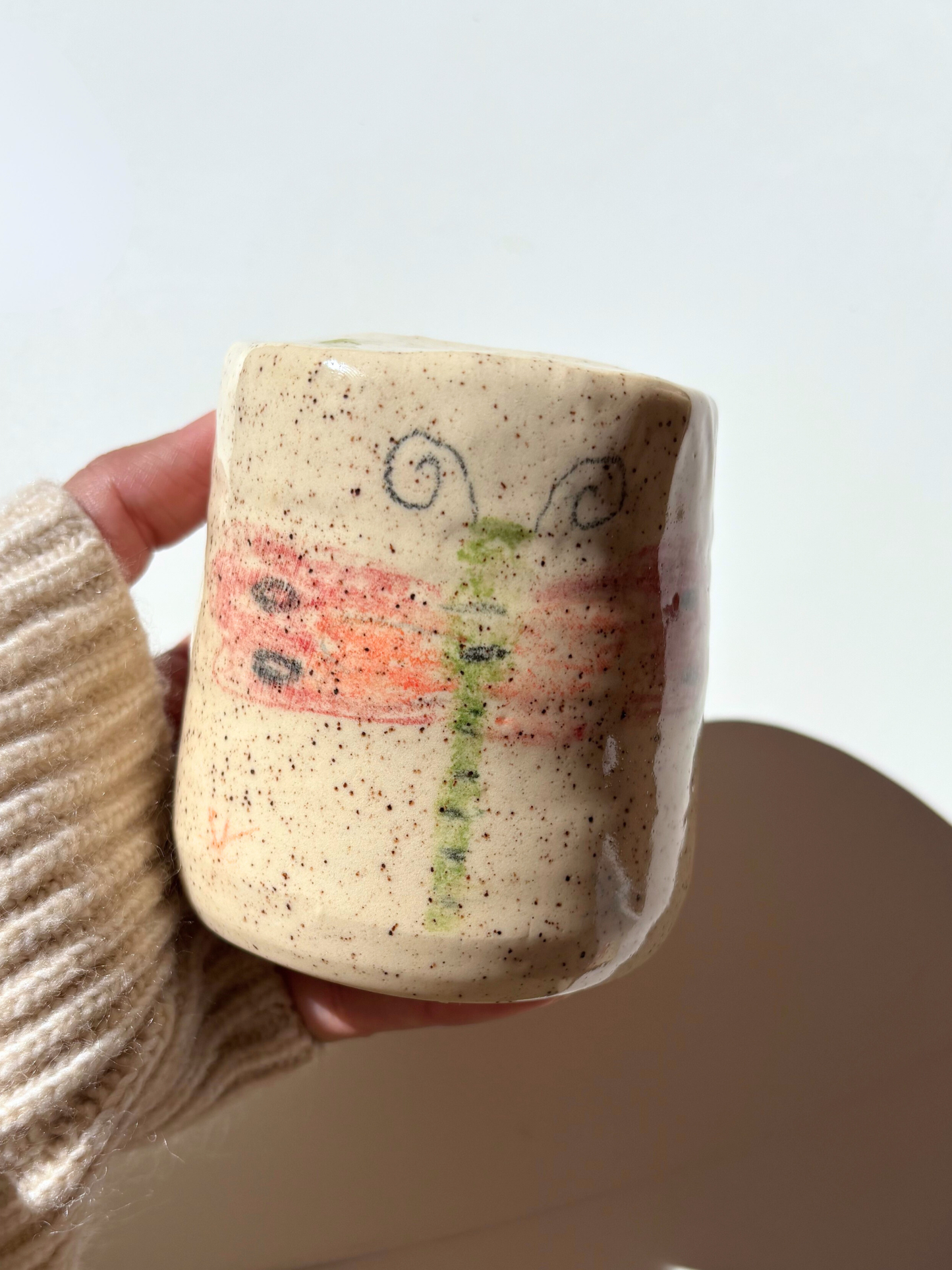 Hand holding a ceramic mug with a ladybug dragonfly design on cute ceramic travel mug