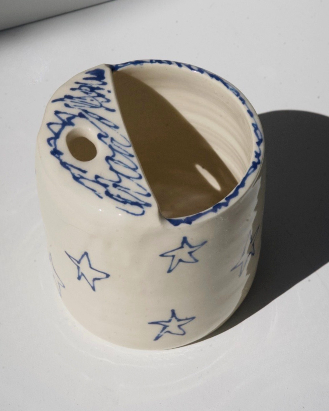 Ceramic travel mug with blue star patterns on a white background